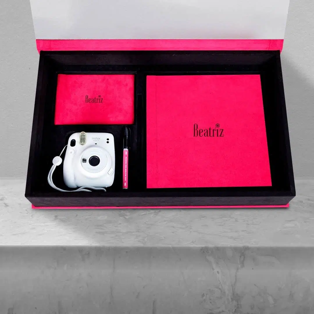 Câmera Instax portátil com acessórios em embalagem elegante rosa e preto.