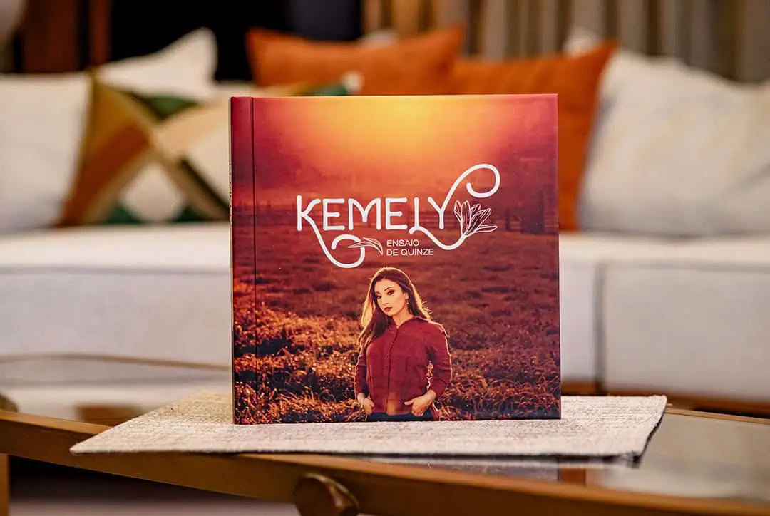 Ensaio fotográfico de capa do livro Kemeiy com capa vermelha e foto de mulher no campo sunset.