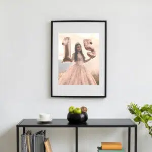 1. Fotos decorativas com moldura preta e balões em forma de número 15 e menina vestida de vestido rosa.