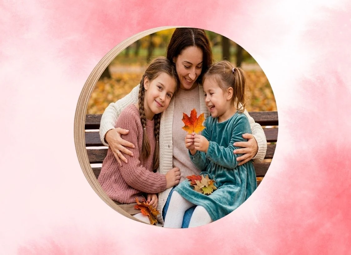 Árvore de outono com mãe e duas meninas sorrindo em parque.